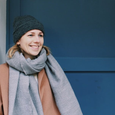 Karina steht vor einer blauen Tür und lächelt.