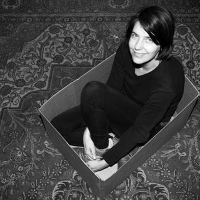 Annette sitzt in einem Karton auf einem Teppich